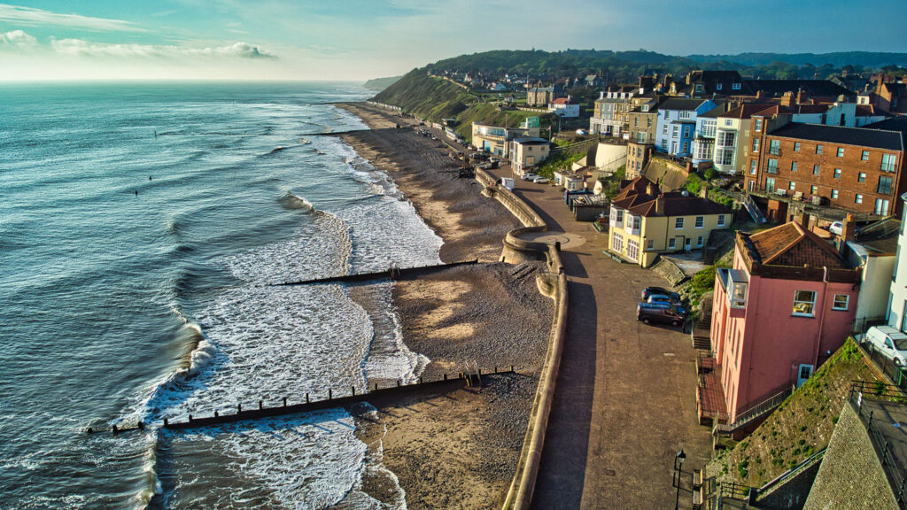 A quaint village stretches along the wild coastline of Norfolk.