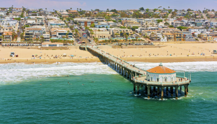 Aerial view of Huntington beach pier and wave splashing on beach against residential district, Orange County, Southern California, California, USA.