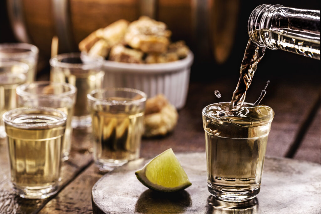 glass of Cachaça, pinga, cana or caninha is the sugar cane brandy, typical drink from Brazil, drops of drink flying, spilling or overflowing, filling the glass