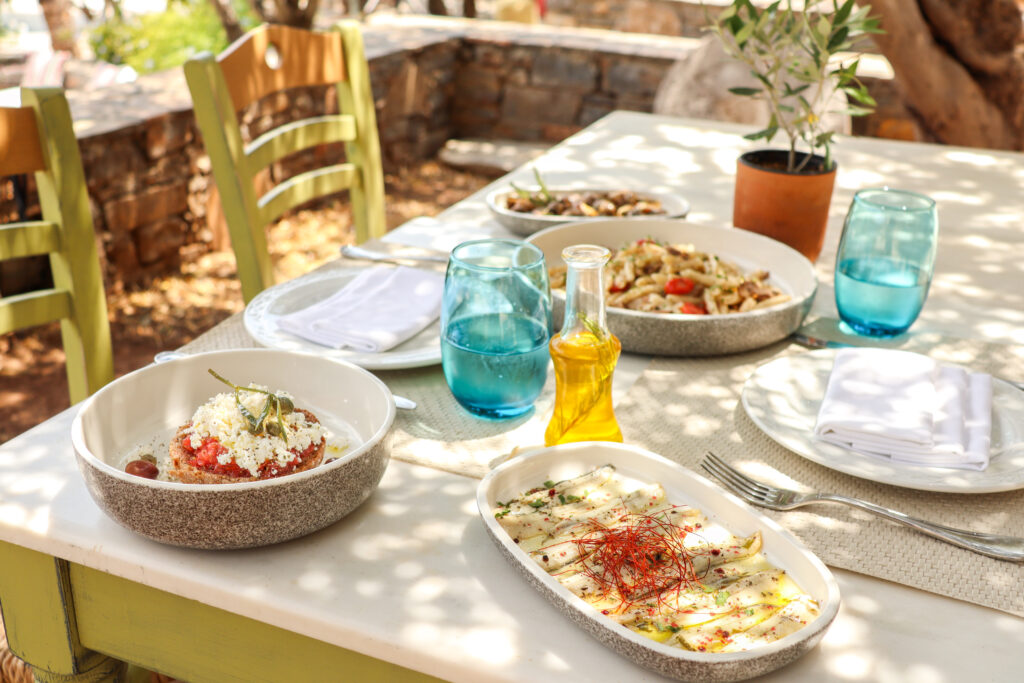 Greek Dinner Table with Food and Plates under olive trees with Cretan delicacies