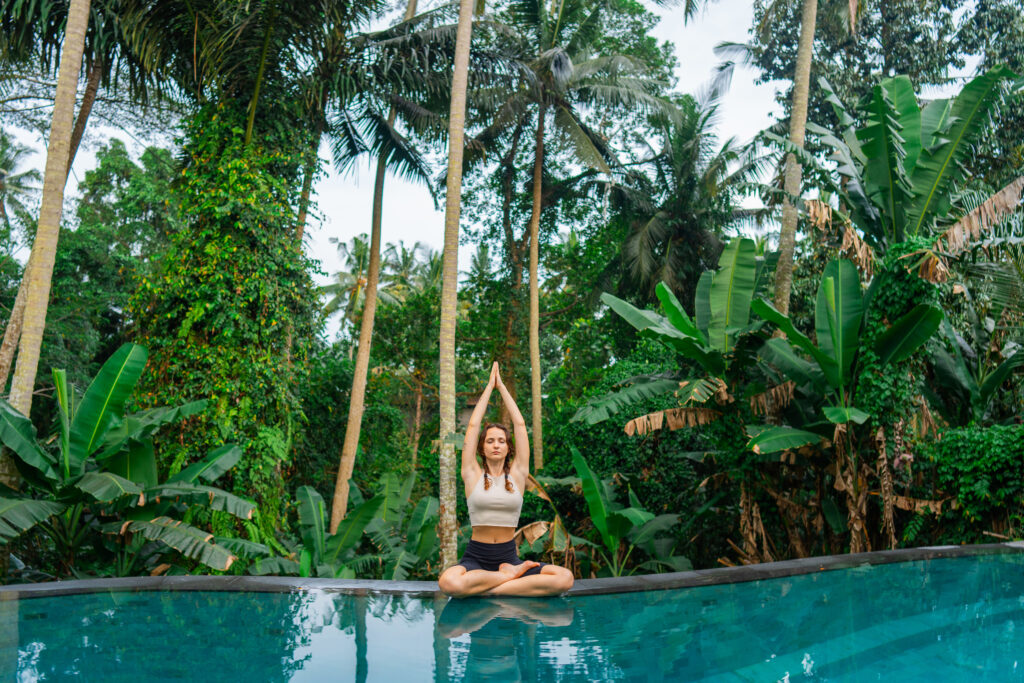 Yoga near the swimming pool among jungles